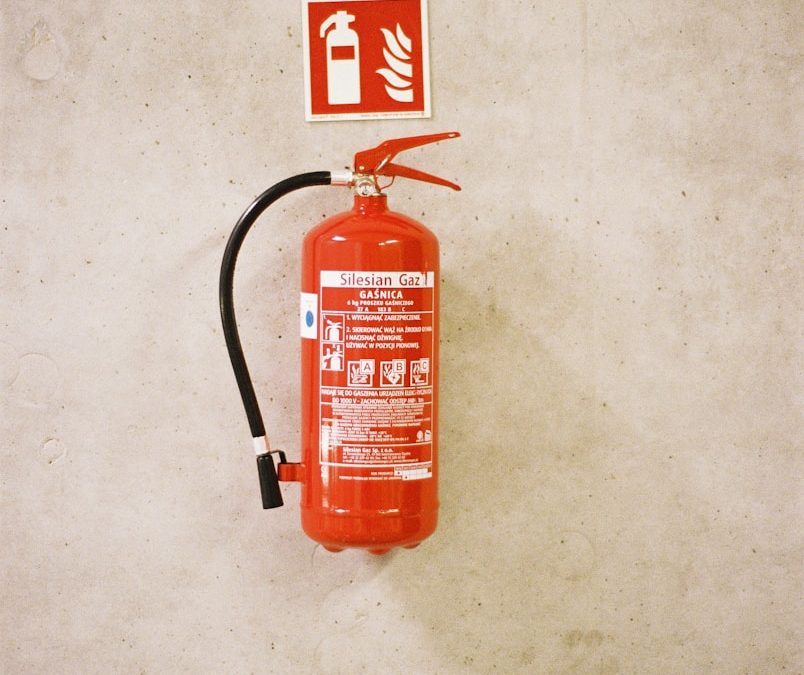 Red fire extinguisher mounted on a concrete wall.